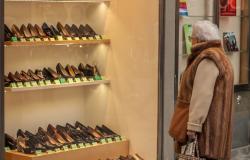 Older Italian woman looks at a store display of shoes