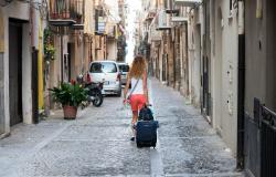 Woman wheels suitcase through streets of Cefalu