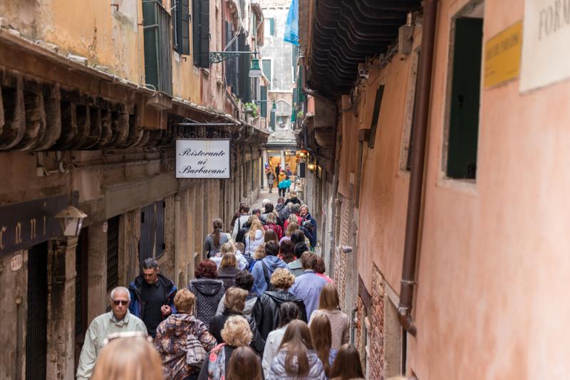 People squeeze down a narrow street in Venice